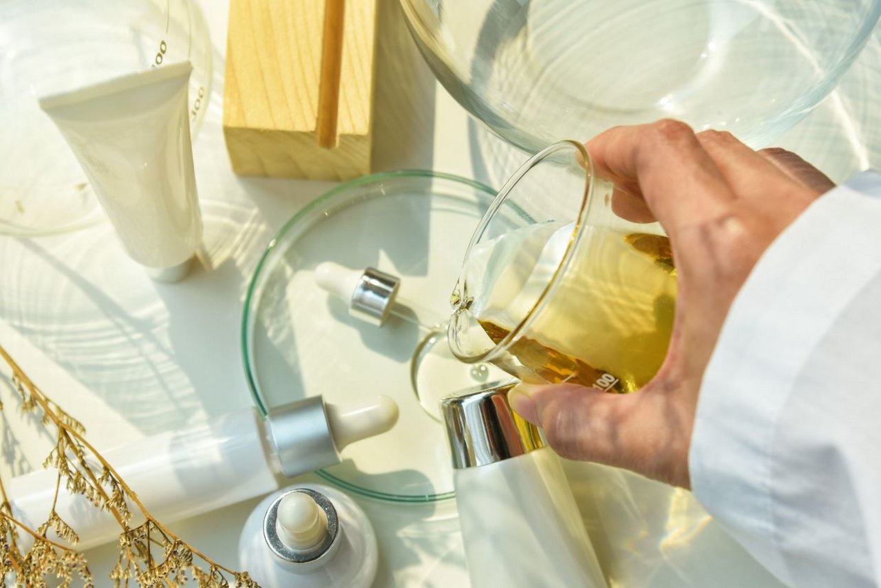 Scientist pouring ingredients in a skincare formulation process, representing anti ageing skincare with plant-based and active skincare ingredients.