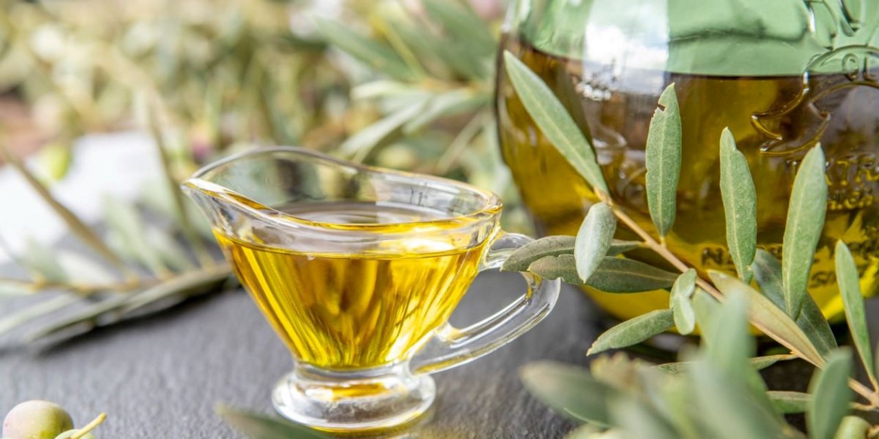 Close-up of a glass container with olive oil and leaves, highlighting natural formulations and sustainable beauty.