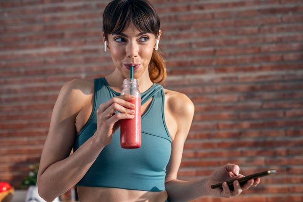 Active woman enjoying a smoothie made with plant based protein powder after a workout for sports nutrition.