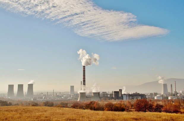 An industrial plant emitting steam and smoke, representing the implementation of circular economy principles of industrial symbiosis.